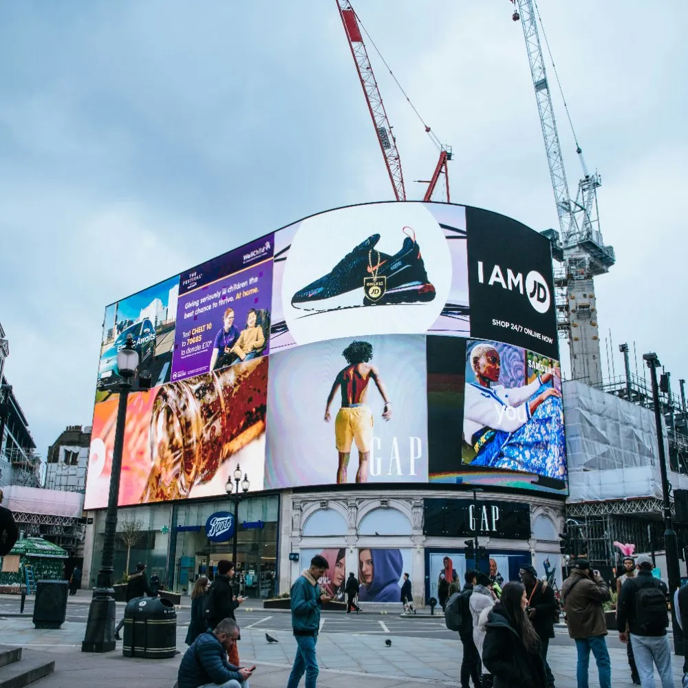 Piccadilly Lights above a crowd, third-party surfaces carrying a brand