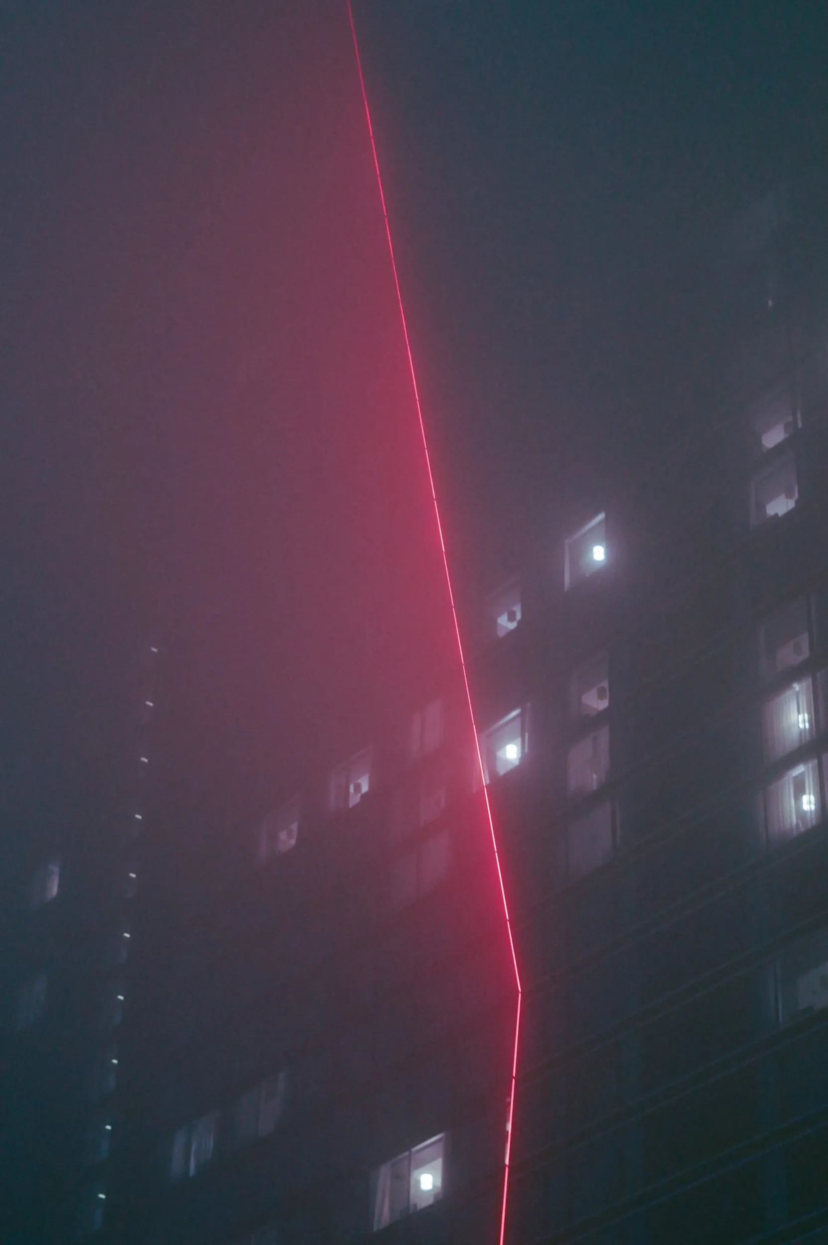 A red laser line against a tower in fog