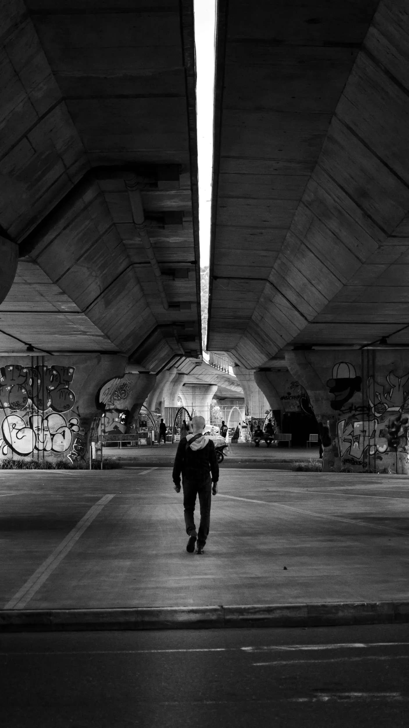A figure walking through a concrete underpass