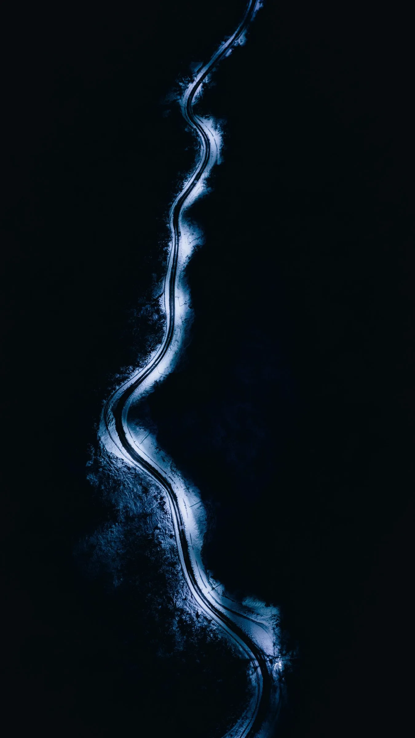 A winding road traced in light at night